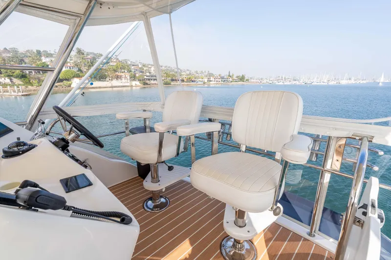 Roll The Dice Yacht Photos Pics Helm of 2005 Riviera 47 Convertible yacht with ocean view and white captain chairs.