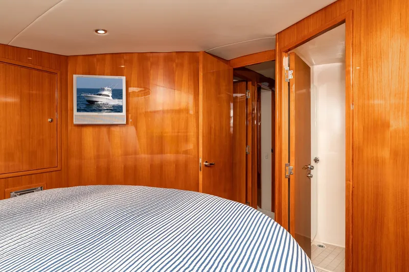 Roll The Dice Yacht Photos Pics Interior of 2005 Riviera 47 Convertible yacht with wood paneling and striped bedding.