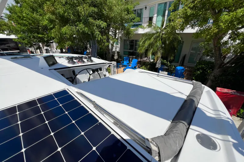 Ke'ala Yacht Photos Pics 2021 Balance 482 catamaran with solar panels, docked near lush greenery and blue chairs.