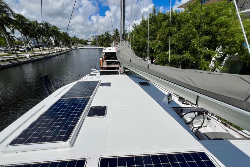 Ke'ala Yacht Photos Pics Sailboat with solar panels on deck, Balance 482 model, cruising a canal lined with palm trees.