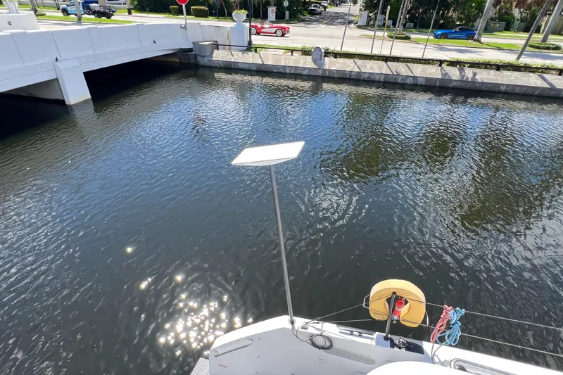 Ke'ala Yacht Photos Pics A 2021 Balance 482 catamaran with a satellite dish, docked near a bridge over calm water.