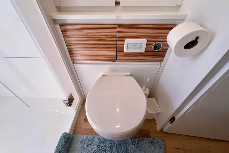 Ke'ala Yacht Photos Pics Modern bathroom with Balance 482 toilet, wooden paneling, and blue rug, 2021 model.