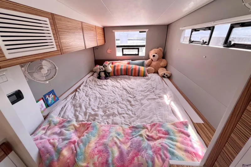 Ke'ala Yacht Photos Pics Cozy camper bedroom with plush toys, colorful blanket, and wooden cabinets in Balance 482 model.