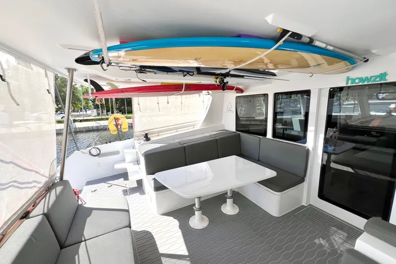 Ke'ala Yacht Photos Pics Luxurious 2021 Balance 482 catamaran interior with surfboards, seating, and dining area.