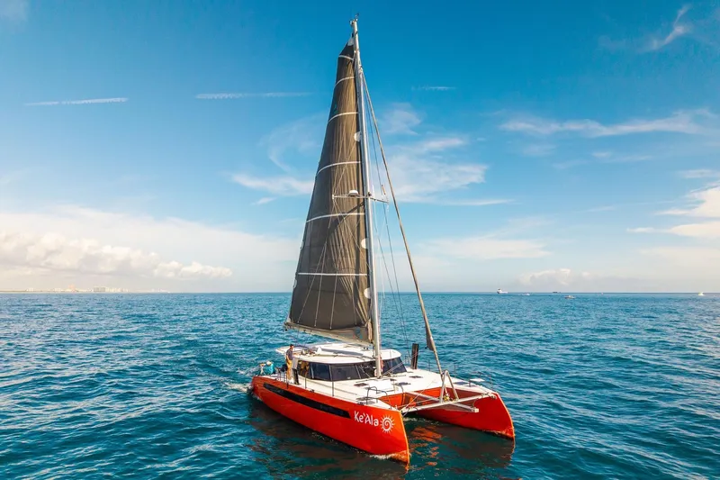 Ke'ala Yacht Photos Pics Red Balance 482 catamaran sailing on open sea under clear blue sky, 2021 model.