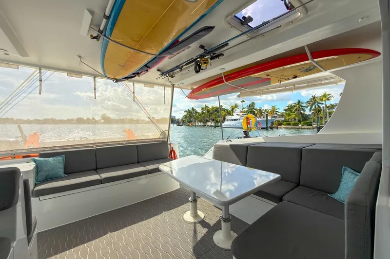 Ke'ala Yacht Photos Pics Luxurious 2021 Balance 482 yacht interior with surfboards, overlooking serene waterfront and palm trees.