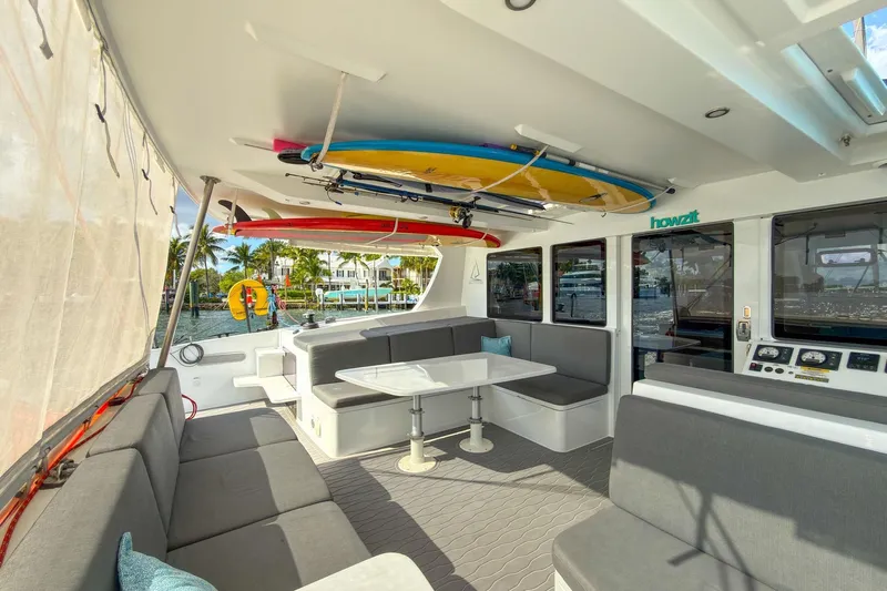 Ke'ala Yacht Photos Pics Luxurious 2021 Balance 482 yacht interior with seating, surfboards, and scenic marina view.