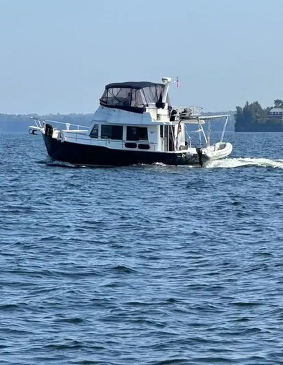Mano 1 Yacht Photos Pics 2011 Mainship 395 Trawler cruising on a calm lake under clear skies.