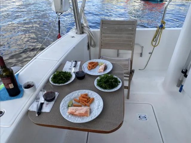 Mano 1 Yacht Photos Pics Outdoor dining setup on 2011 Mainship 395 Trawler with salmon, greens, and wine.