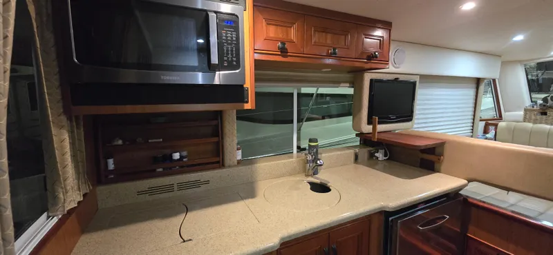 Mano 1 Yacht Photos Pics 2011 Mainship 395 Trawler kitchen with microwave, sink, and TV in cozy interior.