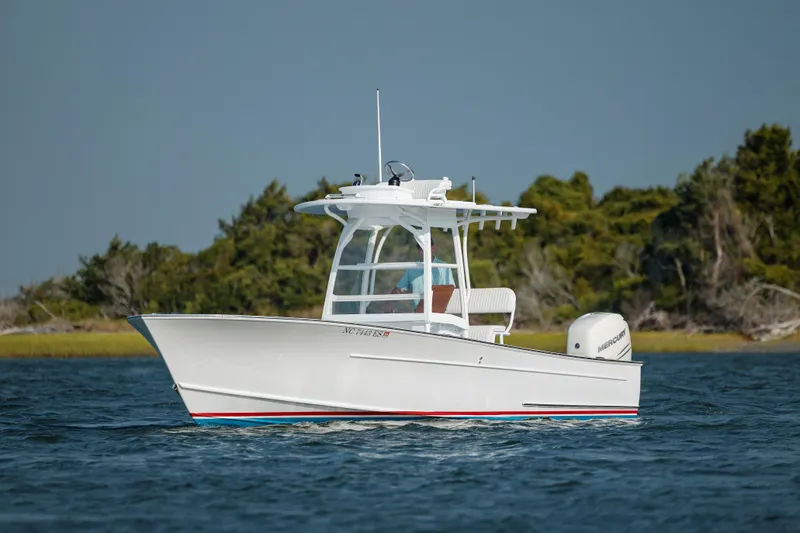  Yacht Photos Pics 2019 Gamefisherman 26 Cuddy Cabin boat on water, with lush greenery in the background.