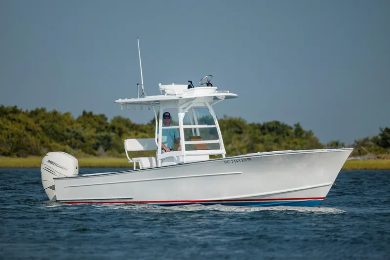  Yacht Photos Pics 2019 Gamefisherman 26 Cuddy Cabin boat cruising on water, with lush greenery in the background.
