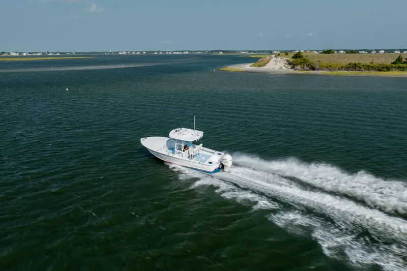  Yacht Photos Pics 2019 Gamefisherman 26 Cuddy Cabin cruising on open water near a scenic shoreline.