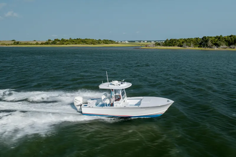  Yacht Photos Pics 2019 Gamefisherman 26 Cuddy Cabin cruising on open water near a scenic shoreline.