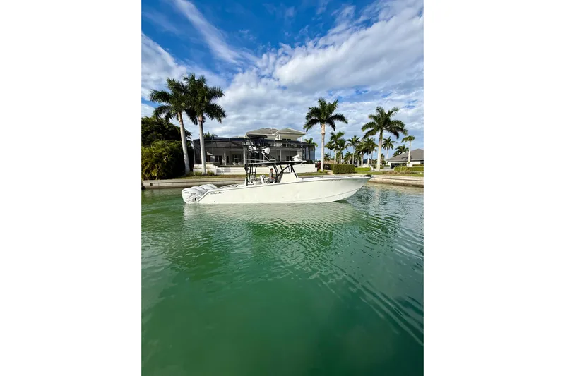  Yacht Photos Pics 2020 SeaHunter 41 CTS boat on calm water, surrounded by palm trees and a modern house.