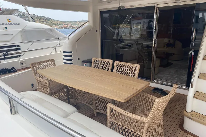 75 Princess 2008 Yacht Photos Pics Outdoor dining area on 2008 Princess 75 Motor Yacht with wicker chairs and wooden table.