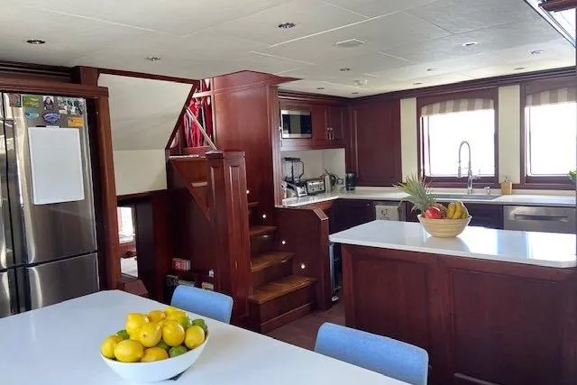 Samsara Yacht Photos Pics Luxurious yacht kitchen with wooden cabinetry, stainless steel appliances, and fruit bowls, Custom Dauntless 2017.