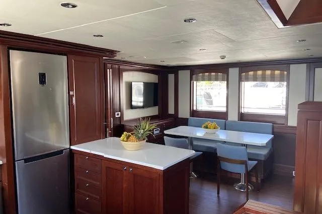Samsara Yacht Photos Pics Luxurious yacht interior with modern kitchen and dining area, featuring wood cabinetry and large windows.
