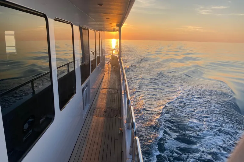 Samsara Yacht Photos Pics Dauntless Custom 2017 yacht cruising at sunset, reflecting on calm ocean waters.