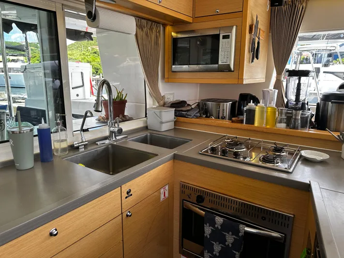 Flotation Therapy Yacht Photos Pics Modern kitchen interior on a 2019 Lagoon 450F yacht, featuring a stove, sink, and microwave.