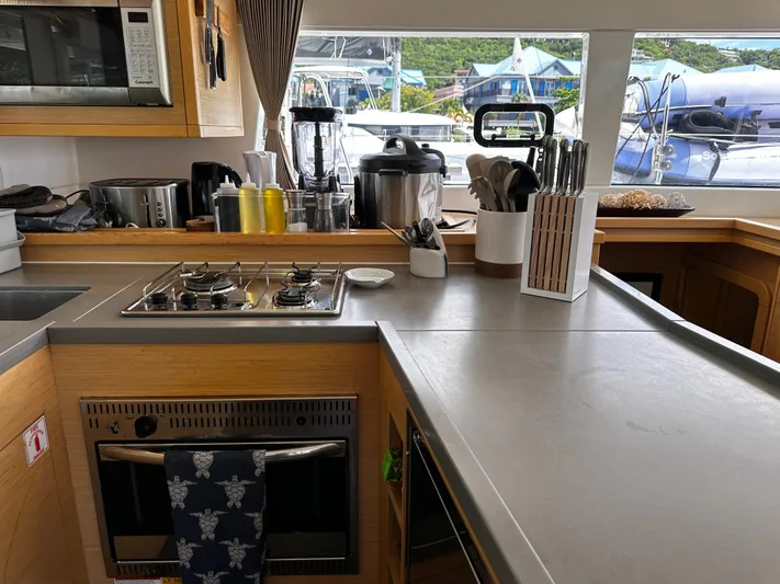 Flotation Therapy Yacht Photos Pics Modern kitchen interior on a 2019 Lagoon 450F yacht, featuring appliances and a scenic marina view.