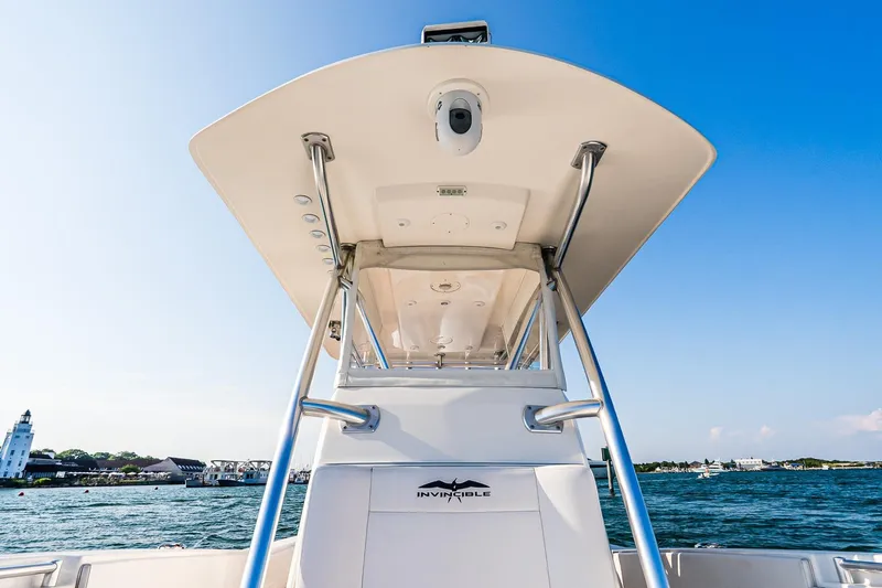 Blue Eyes Yacht Photos Pics 2016 Invincible 33 Open Fisherman boat on water, clear sky, coastal background.