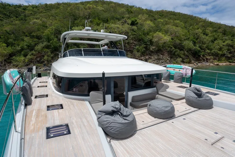 Cest La Vie Yacht Photos Pics Luxurious 2022 Lagoon SIXTY 7 yacht with spacious deck and scenic coastal backdrop.