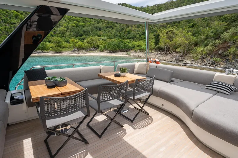 Cest La Vie Yacht Photos Pics Luxurious 2022 Lagoon SIXTY 7 yacht deck with seating, tables, and scenic coastal view.