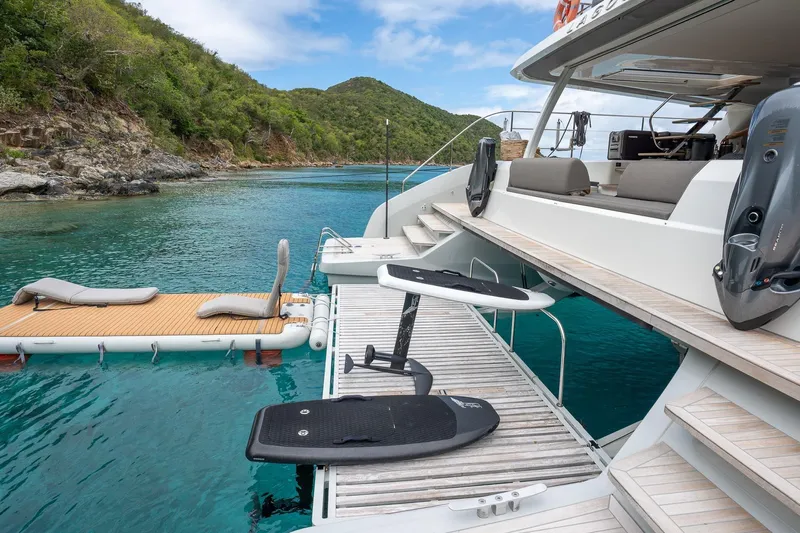 Cest La Vie Yacht Photos Pics Luxurious 2022 Lagoon SIXTY 7 yacht with water toys and scenic coastal backdrop.