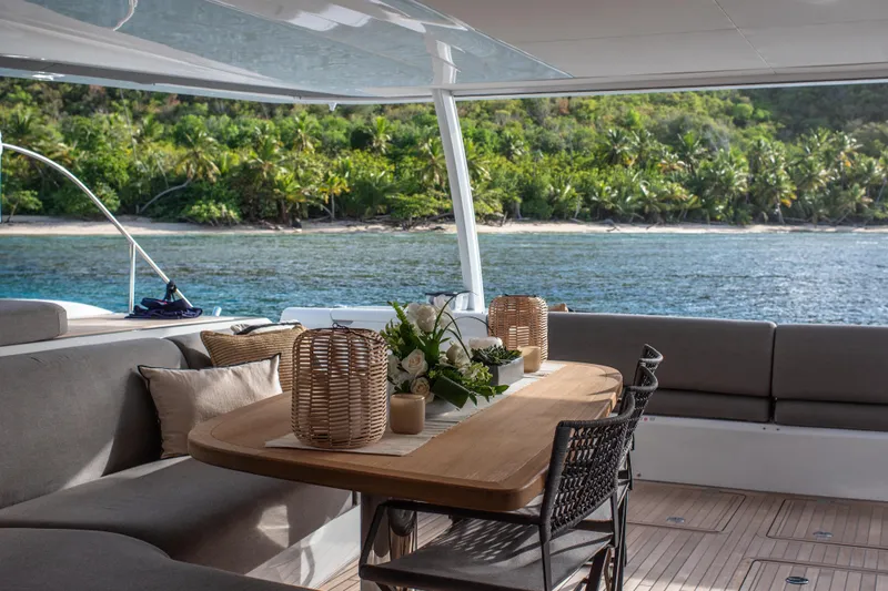 Cest La Vie Yacht Photos Pics Luxurious Lagoon SIXTY 7 yacht interior with elegant dining area overlooking tropical shoreline, 2022 model.