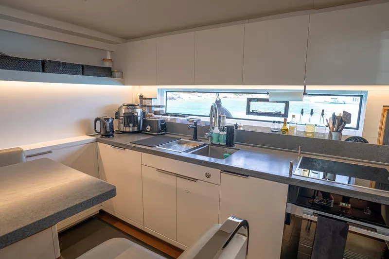 Cest La Vie Yacht Photos Pics Modern kitchen interior on 2022 Lagoon SIXTY 7 yacht, featuring sleek countertops and appliances.