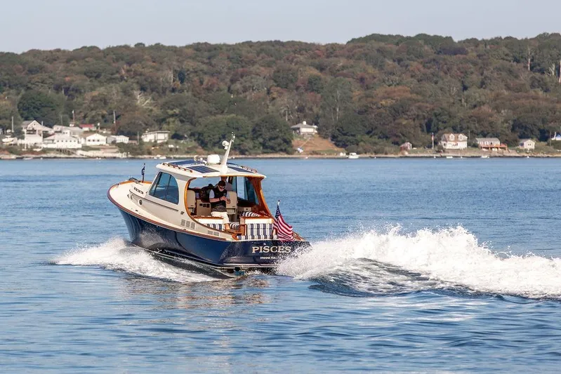 Pisces Yacht Photos Pics 2017 Hinckley Picnic Boat MKIII cruising on a scenic lake with shoreline houses.