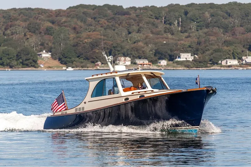 Pisces Yacht Photos Pics 2017 Hinckley Picnic Boat MKIII cruising on a scenic lake with shoreline houses.
