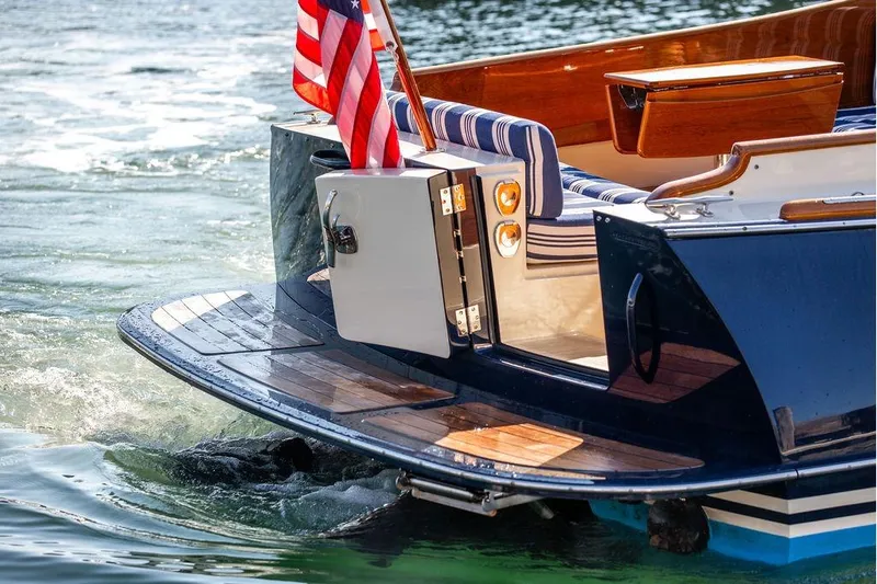Pisces Yacht Photos Pics 2017 Hinckley Picnic Boat MKIII with American flag, elegant wooden deck, and striped seating.