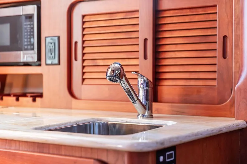 Pisces Yacht Photos Pics Hinckley Picnic Boat MKIII 2017 kitchen with wooden cabinets, stainless steel sink, and microwave.