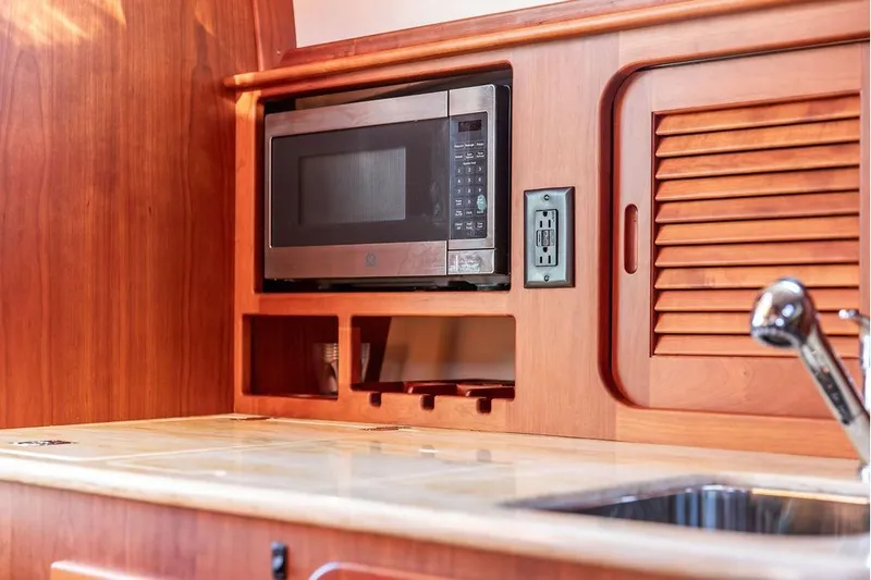 Pisces Yacht Photos Pics Hinckley Picnic Boat MKIII 2017 interior with microwave, wooden cabinetry, and sink.