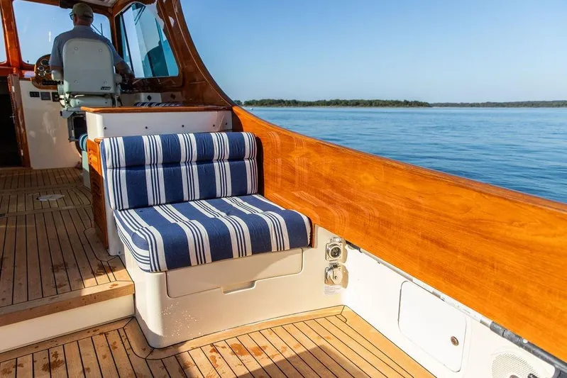 Pisces Yacht Photos Pics 2017 Hinckley Picnic Boat MKIII interior with striped seating, wooden deck, and ocean view.