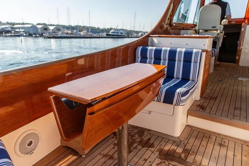 Pisces Yacht Photos Pics 2017 Hinckley Picnic Boat MKIII interior with striped seating and wooden table.
