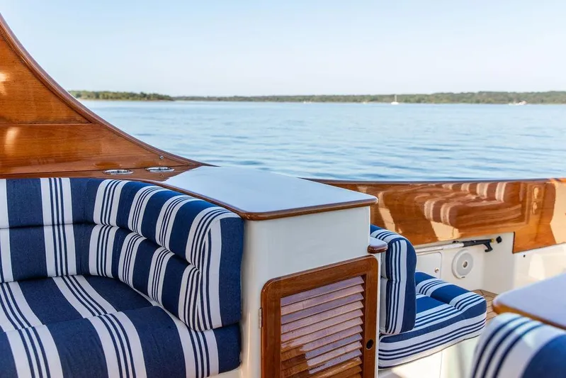 Pisces Yacht Photos Pics 2017 Hinckley Picnic Boat MKIII with striped seating, wooden accents, and scenic water view.