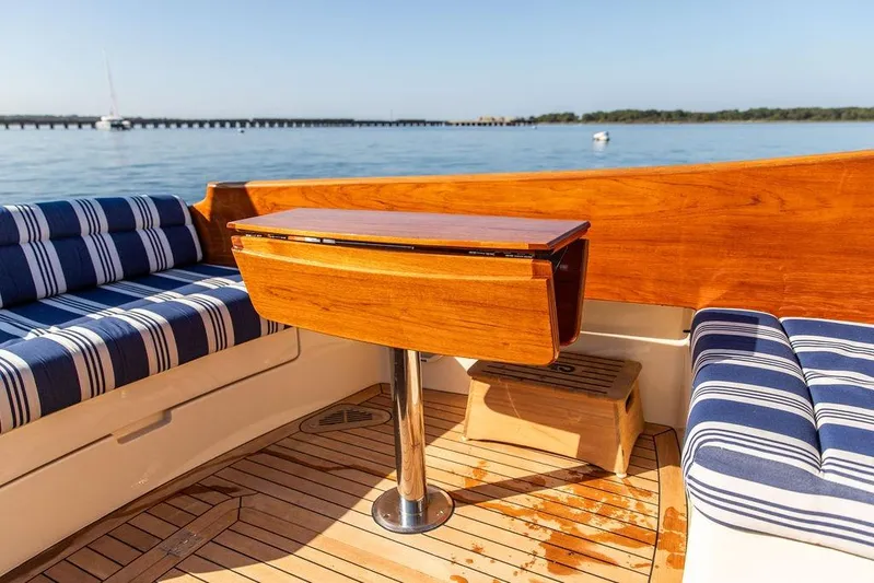 Pisces Yacht Photos Pics Hinckley Picnic Boat MKIII 2017 interior with striped seating and wooden table on deck.