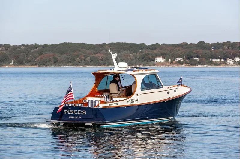 Pisces Yacht Photos Pics 2017 Hinckley Picnic Boat MKIII cruising on calm waters with scenic shoreline backdrop.