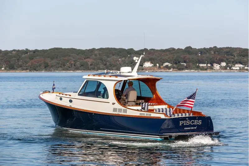 Pisces Yacht Photos Pics 2017 Hinckley Picnic Boat MKIII cruising on calm waters with scenic shoreline backdrop.