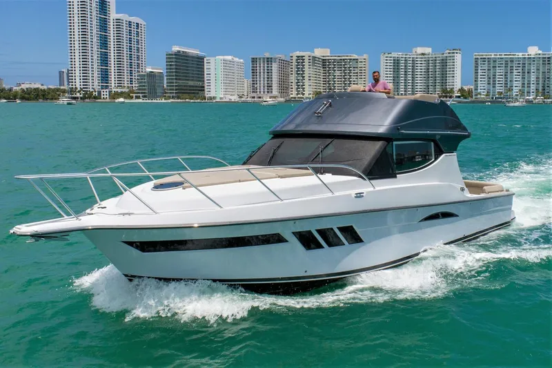  Yacht Photos Pics 2019 Silverton 41 Sport Bridge yacht cruising in turquoise waters near city skyline.