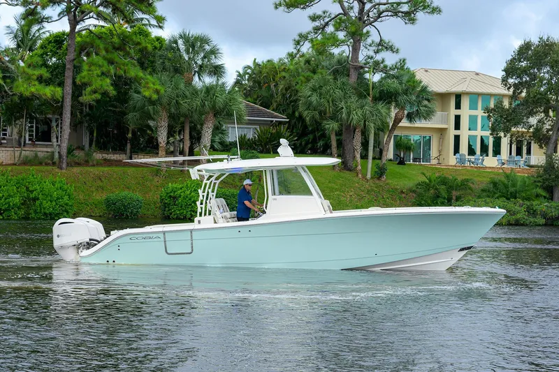 Conched Out Yacht Photos Pics 2020 Cobia 350 CC boat cruising on a scenic waterway near lush greenery.