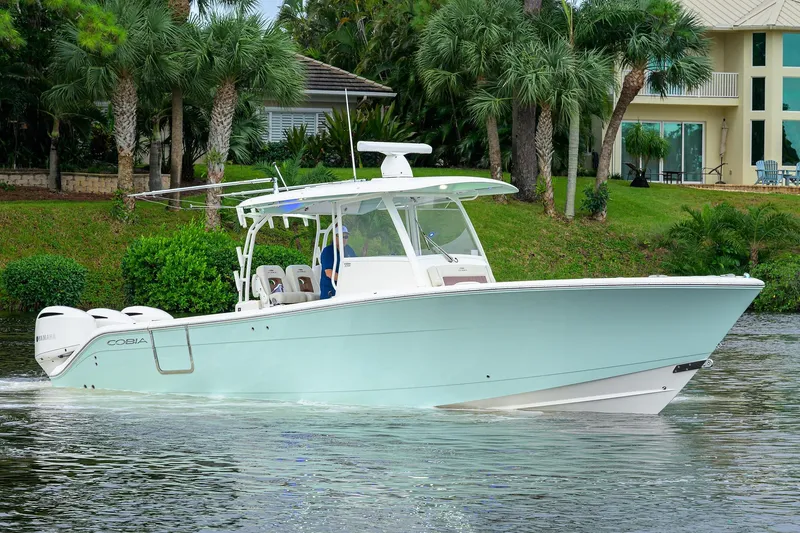 Conched Out Yacht Photos Pics 2020 Cobia 350 CC boat cruising on a scenic waterway with lush greenery.
