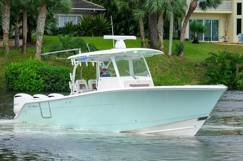 Conched Out Yacht Photos Pics 2020 Cobia 350 CC boat cruising on a scenic waterway with lush greenery.