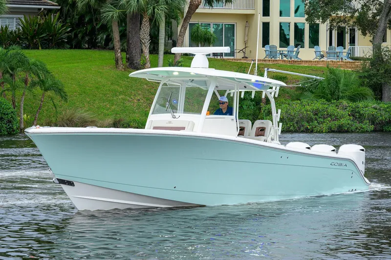 Conched Out Yacht Photos Pics 2020 Cobia 350 CC boat cruising on a scenic waterway near a lush, green shoreline.