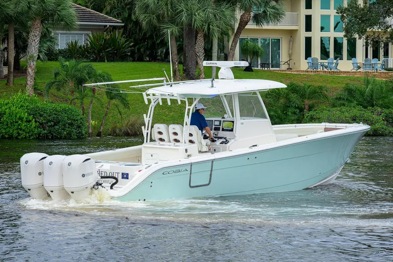 Conched Out Yacht Photos Pics 2020 Cobia 350 CC boat cruising on a scenic waterway near lush greenery.