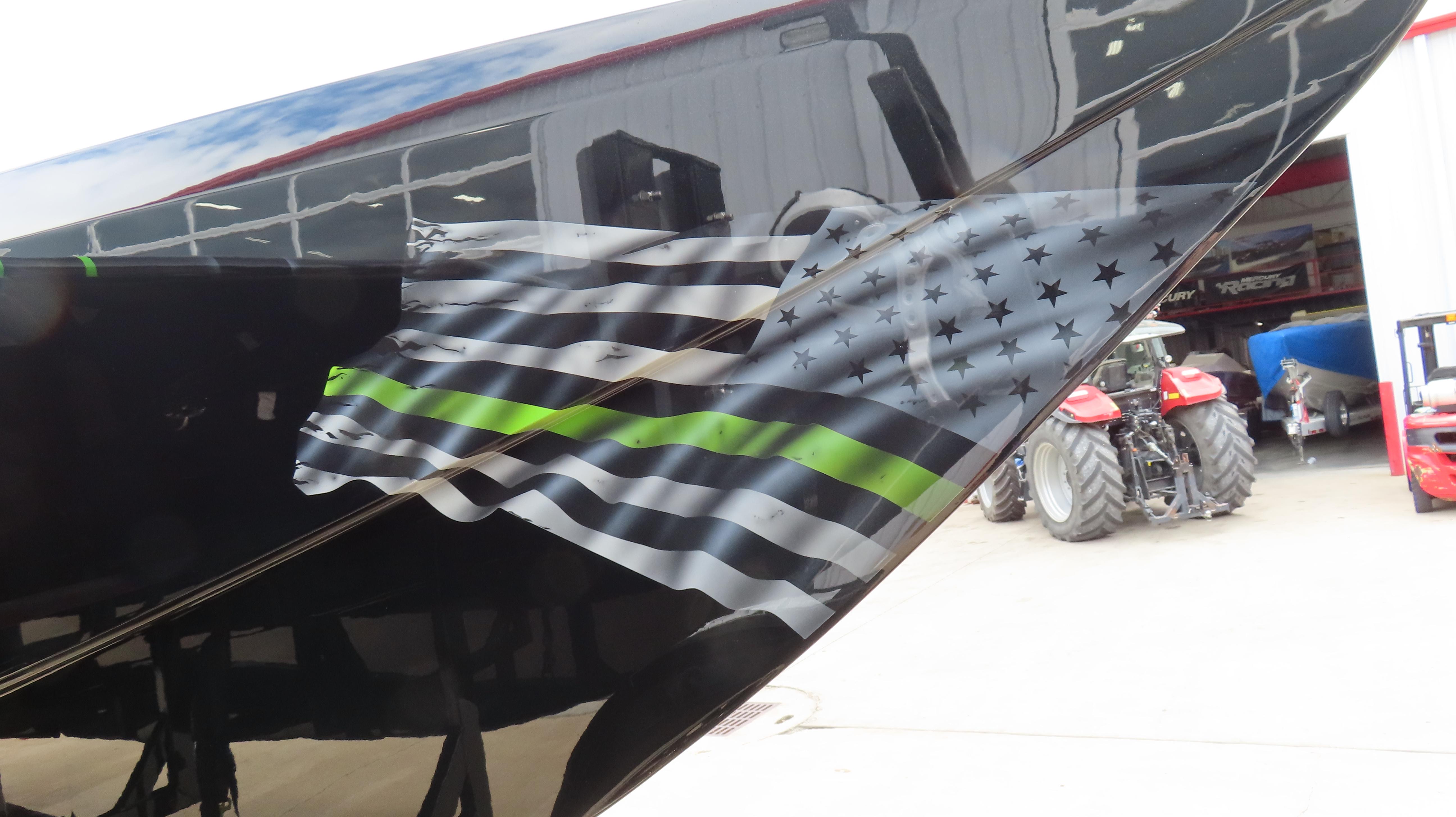 2025 Outerlimits 46 SC boat with black and green flag design on the hull.