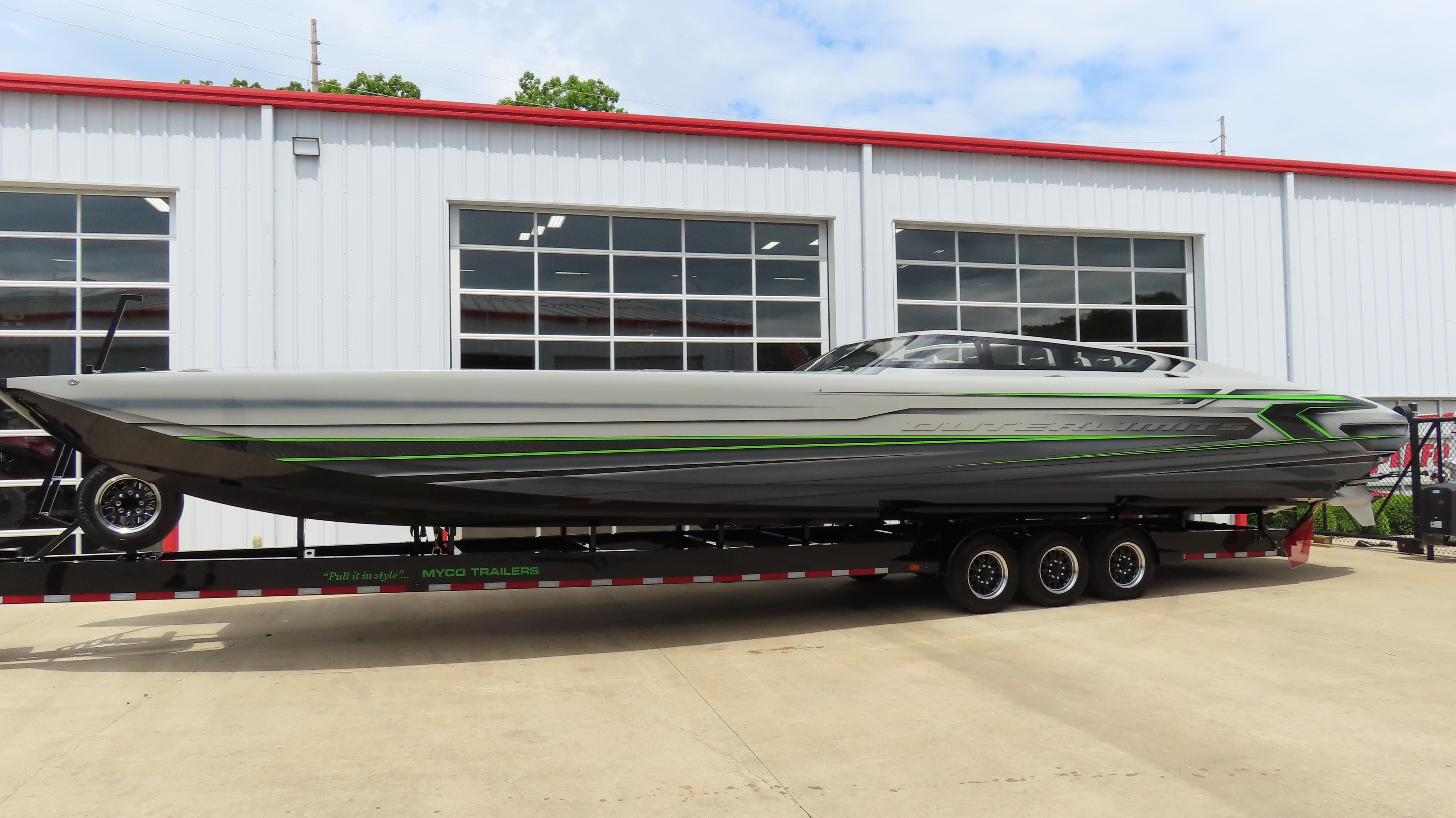 2025 Outerlimits 46 SC powerboat on trailer, sleek design with green accents, parked outside a garage.